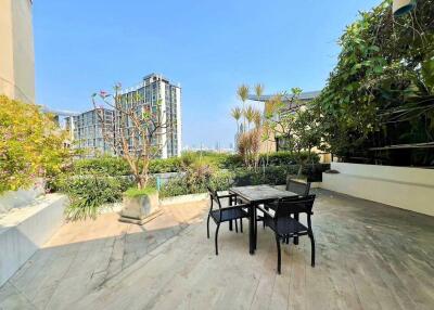 Spacious outdoor patio with table and chairs, lush greenery, and city view