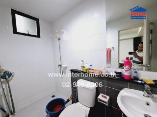 Bathroom with white tiles, glass window, and toiletries on the countertop