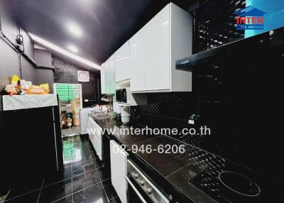 Modern kitchen with black and white decor, featuring appliances and ample storage.