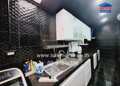 Modern kitchen with black tile walls and white cabinets