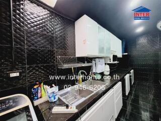 Modern kitchen with black tile walls and white cabinets