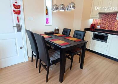 Dining area with black dining table and chairs, adjacent to a kitchen with a microwave and cabinets