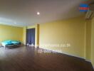 Spacious bedroom with wooden flooring and yellow walls