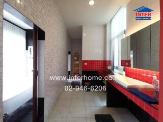 Modern bathroom with red and white tiles, large mirror, and ample storage