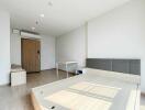 Modern bedroom with a wooden floor, bed frame, desk, and air conditioner