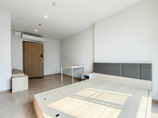 Modern bedroom with a wooden floor, bed frame, desk, and air conditioner