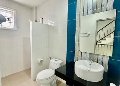Modern bathroom with a large mirror, sink, toilet, and decorative tiles
