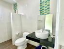 Modern bathroom with sink, toilet, and tiled walls