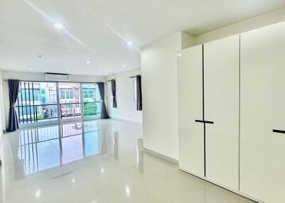Spacious living area with large windows, glossy tile flooring and built-in wardrobe