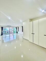 Spacious living area with large windows, glossy tile flooring and built-in wardrobe