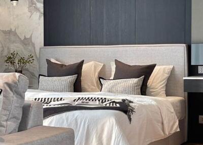 Modern bedroom with grey headboard and pillows, accent wall, and decorative plants