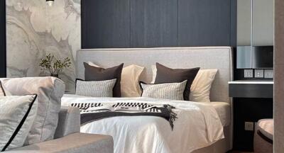 Modern bedroom with grey headboard and pillows, accent wall, and decorative plants