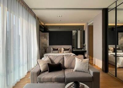 Modern bedroom with a large window, gray sofa, and mirrored wardrobe
