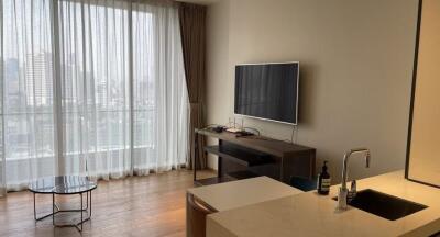 Modern living room with large window, TV, and kitchen counter