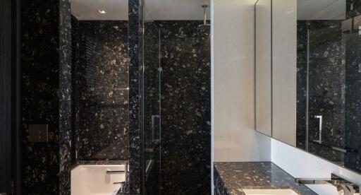 Modern bathroom with dark marble walls, a bathtub, and large mirrors
