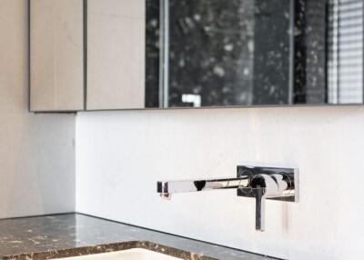 Modern bathroom sink with marble countertop and wall-mounted faucet