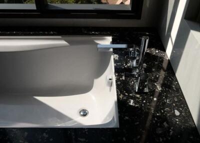 Modern bathroom with a sleek white bathtub and black marble countertops