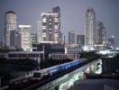 Night view of city skyline with tall buildings and train