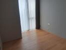 Empty bedroom with wooden floor and curtains on large window