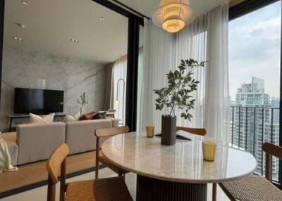 Modern living room with large windows, a dining table, and a view of the city