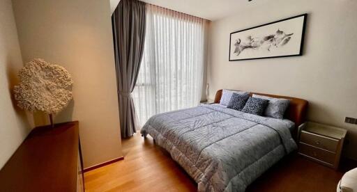 Bedroom with a large window, curtains, double bed, and a framed picture