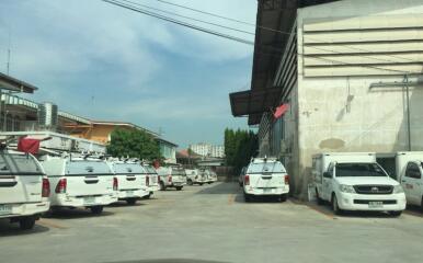 Parking area with multiple white vehicles near an industrial building