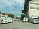 Parking area with multiple white vehicles near an industrial building