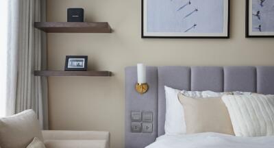 Cozy bedroom with minimalist decor, including wall shelves, framed art, and a cushioned headboard