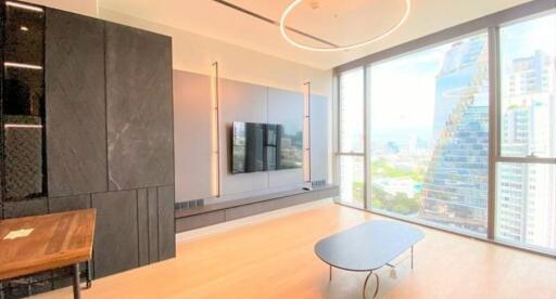 Modern living room with city view featuring a large window, mounted TV, and minimalist furniture