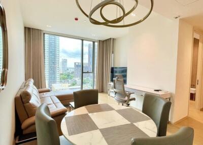 Modern living room with a city view, featuring a sofa, dining table, TV, and office chair.