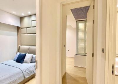 Modern bedroom with grey upholstered bed and blue accents featuring ensuite bathroom and hallway view