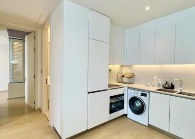 Modern kitchen with white cabinetry, integrated appliances, and a washing machine