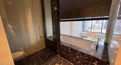 Modern bathroom with marble elements, glass shower, and city view