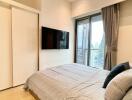 Modern bedroom with a bed, wall-mounted TV, and access to a balcony