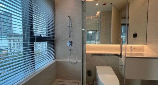 Modern bathroom with large window, shower, toilet, and vanity with sink.