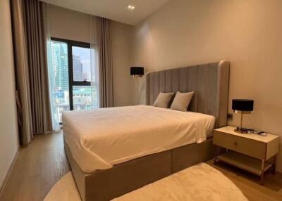 Spacious bedroom with a large bed, modern furnishings, and a window with city view