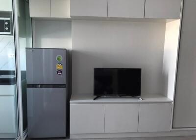Modern kitchen area with refrigerator and wall-mounted TV