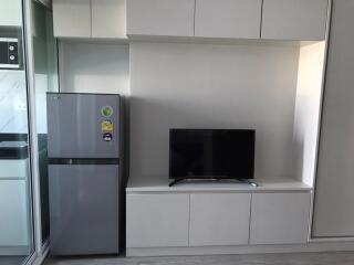 Modern kitchen area with refrigerator and wall-mounted TV