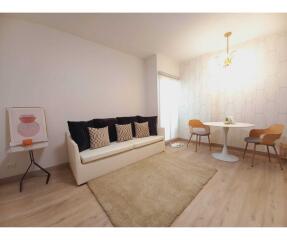 Cozy living room with a sofa, rug, and dining area with a table and chairs.