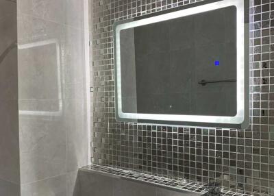 Modern bathroom with LED-lit mirror and mosaic tile wall