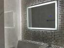 Modern bathroom with LED-lit mirror and mosaic tile wall