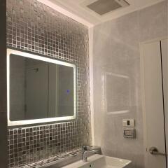 Modern bathroom with illuminated mirror and mosaic tiles