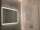 Modern bathroom with illuminated mirror and mosaic tiles