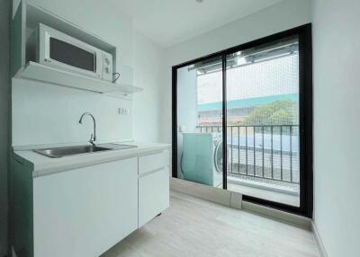 Compact kitchenette with modern appliances and balcony access