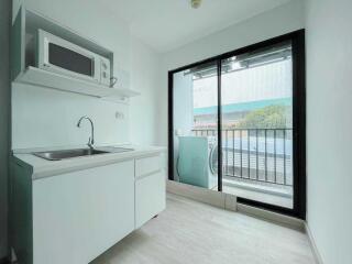 Compact kitchenette with modern appliances and balcony access