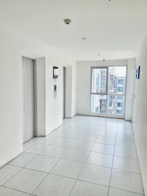 Bright hallway with white tiles and an elevator entrance