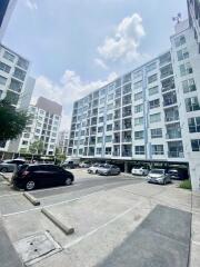 Exterior view of a multi-story residential building with a parking area