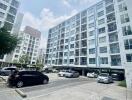 Exterior view of a multi-story residential building with a parking area