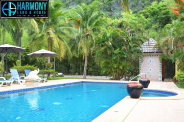 Outdoor swimming pool surrounded by palm trees and lounge chairs