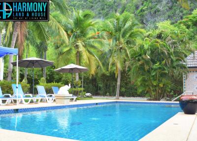 Luxury outdoor swimming pool area with lounge chairs, umbrellas, and lush greenery
